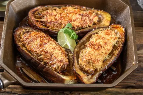 Berenjena airfryer rellena y gratinada, servida en una sartén de hierro fundido con un toque de lima.