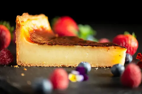 Tranche de flan pâtissier onctueux, avec une croûte dorée et des fruits rouges frais. Un délice pour les yeux et les papilles.