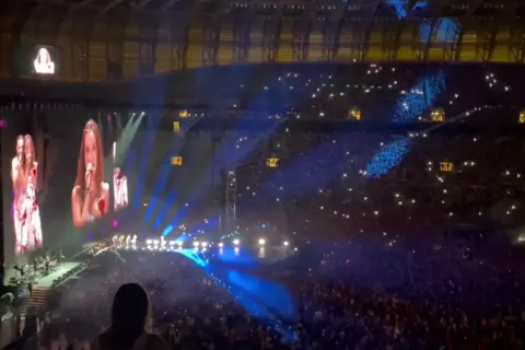 Wielki koncert w Gdańsku 2025! Widownia rozświetlona tysiącami świateł, na scenie artystki śpiewają do mikrofonów, a na telebimach ich zbliżenia.