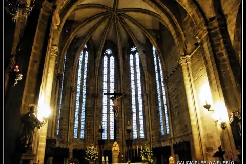 Interior de la iglesia San Francisco de Viveiro, con un crucifijo imponente y vitrales góticos.