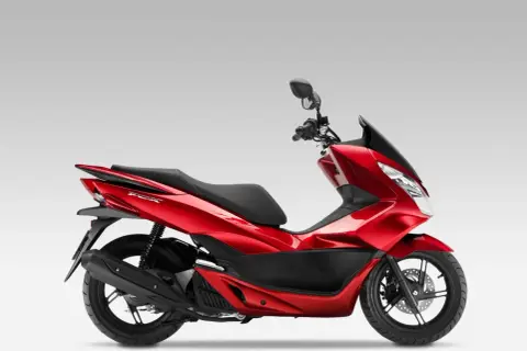 Czerwony skuter Honda PCX 125 na białym tle, widok z boku.