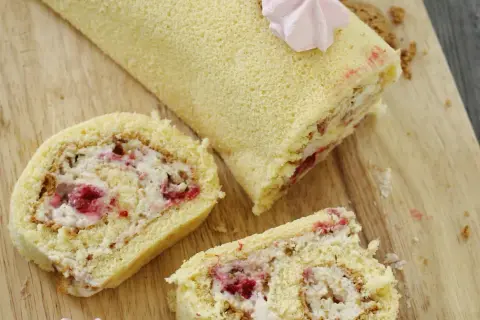 Puszysta rolada biszkoptowa z mascarpone i malinami, udekorowana różową bezą. Idealna na deser.