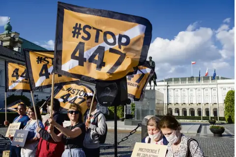 Protestujący trzymają flagi z napisem #STOP 447, sprzeciwiając się ustawie 447. W tle Pałac Prezydencki.