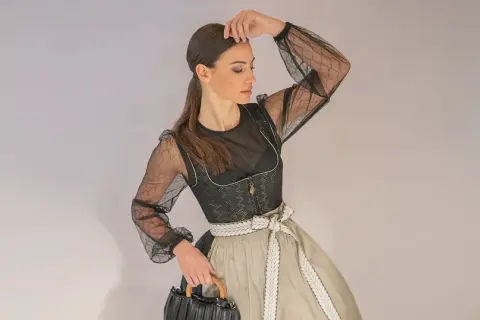 Frau im modernen mini dirndl extra kurz mit transparentem Oberteil und auffälliger Schürze.