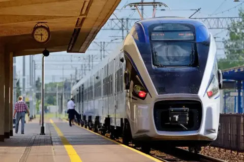 Pociąg Intercity na peronie. Zastanawiasz się, czy można jechać wcześniejszym pociągiem Intercity? Zegar na stacji pokazuje czas.