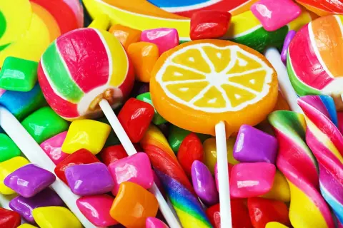 Un surtido vibrante de dulces, incluyendo piruletas, caramelos de goma y bastones de caramelo, que evocan la alegría de los dulces en inglés.