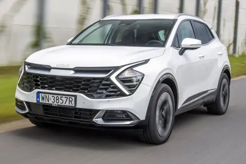 Biała Kia Sportage 1.6 benzyna w ruchu, z widocznym grillem i reflektorami.