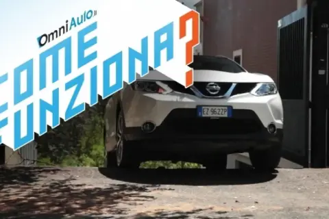 Nissan bianco su strada in salita, con testo "Come funziona?". Spiegazione del sistema hill holder.