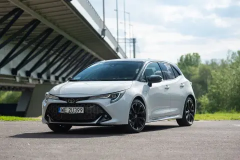 Biała Toyota Corolla GR Sport z czarnymi felgami stoi pod mostem.