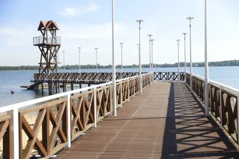 Drewniane molo z wieżą ratowniczą i latarniami nad jeziorem. Idealne miejsce na spacer, może nawet w ramach wypoczynku w Pogoria 3.