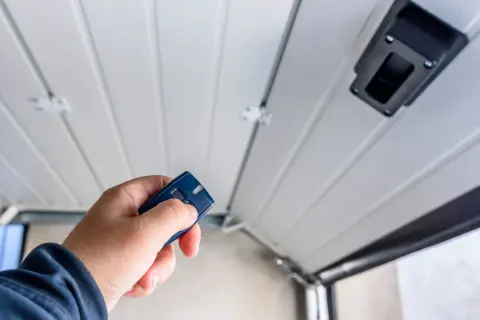 Main tenant utilise une télécommande pour motoriser une porte de garage.