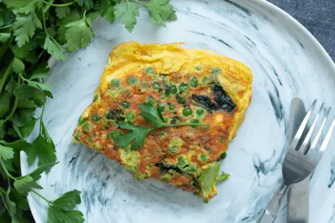 Une omelette aux petits pois et brocolis, garnie de persil frais. Une recette simple et savoureuse pour un repas léger.