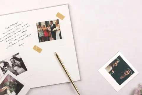 Vœux de mariage manuscrits sur un album, avec des photos instantanées de la cérémonie et du couple. Un stylo doré repose à côté.