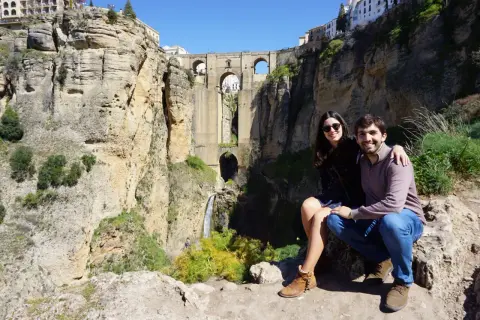 Pareja sonriente posa ante el Puente Nuevo de Ronda, una maravilla para visitar en Ronda en 1 día.