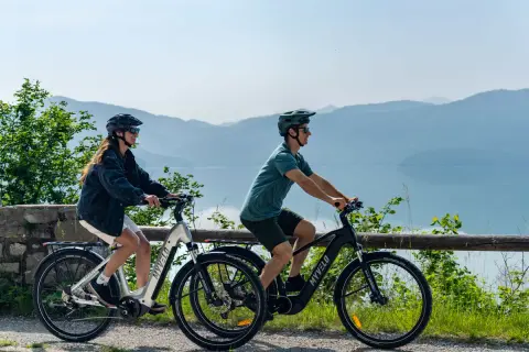 Zwei Personen genießen e bike touren mit Blick auf einen See und Berge.