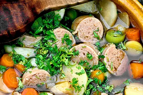 En närbild på en mustig korvgryta med potatis, morötter och purjolök, toppad med färsk persilja. Ett perfekt korvgryta recept för kalla dagar.