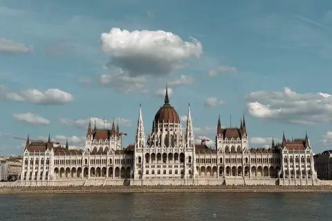 Majestatyczny Parlament w Budapeszcie i okolice, odbijający się w spokojnej wodzie Dunaju.