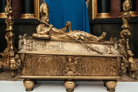Złota trumna z postacią śś. Wojciecha, jego atrybuty: pastorał i księga. Bogate płaskorzeźby przedstawiają sceny z życia świętego.