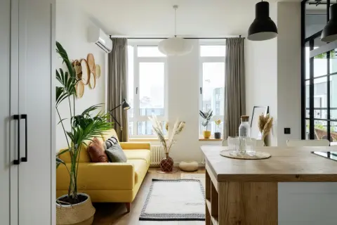 Canapé jaune vif dans un salon lumineux avec des plantes et des paniers décoratifs.