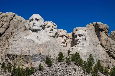 Las caras de cuatro presidentes de EE.UU. talladas en el **Monte Rushmore**, bajo un cielo azul intenso.