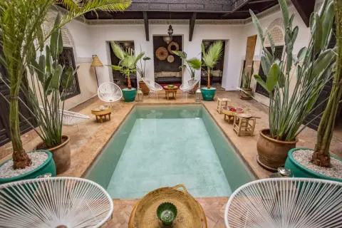 Ein Riad in Marokko: Ein Innenhof mit Pool, Pflanzen und Sitzgelegenheiten, typisch für marokkanische Architektur.