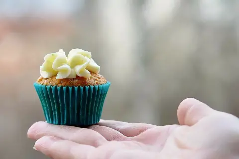 En hand håller en vackert dekorerad muffin, redo att baka muffins.