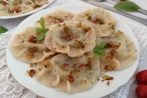 Pyszne pierogi ze szpinakiem, posypane skwarkami i ziołami. Idealne z sosem czosnkowym lub kwaśną śmietaną.