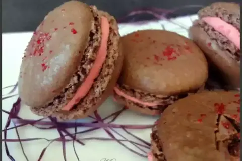 Macarons au chocolat avec ganache framboise et une touche de gélatine pour la brillance.