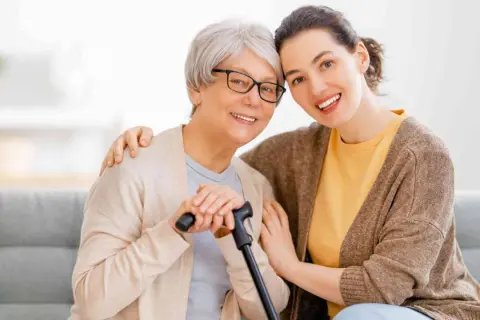 Un modello ap70: due donne sorridono, una anziana con bastone e occhiali, l'altra più giovane con un abbraccio.