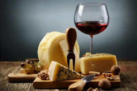 En härlig ost och vinprovning med olika ostar, vindruvor, nötter och ett glas rött vin.