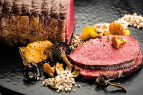 Zarter Rinderbraten im Ofen, serviert mit Pilzen und Quinoa. Ein Festmahl für Genießer.