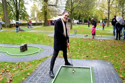 Frau spielt Minigolf in Hennef, im Hintergrund spielen weitere Personen.