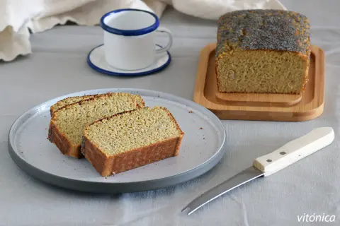 Rebanadas de bizcocho sin azucar con semillas de amapola, servidas en un plato gris junto a una taza y un cuchillo.