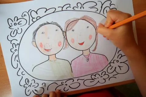 Dziecko kończy rysować portret mamy i taty w ozdobnej ramce. To piękny szablon rodzinny.