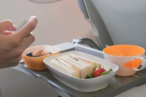 Na tacy w samolocie kanapki i przekąska. Czy w bagażu podręcznym można mieć jedzenie? Tak, jak widać na zdjęciu.