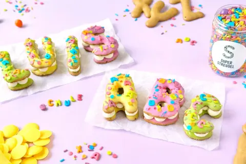 Bunte Buchstabenkekse, inspiriert von einem russisch brot rezept, mit Zuckerguss und Streuseln verziert.