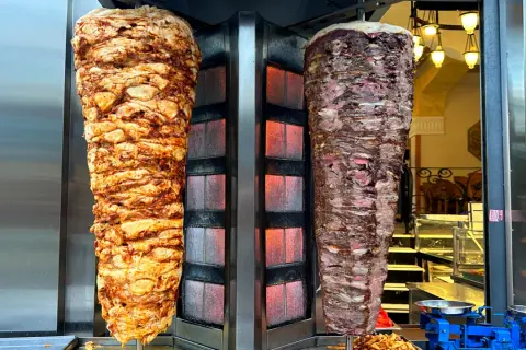 Dwa pionowe rożny z mięsem do kebaba, jeden z kurczaka, drugi wołowy. Zastanawiasz się, ile kcal ma mały kebab?