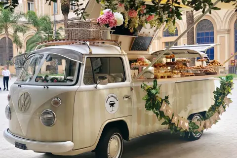 Un furgone vintage allestito per un aperitivo fuori chiesa matrimonio, con fiori e dolci.