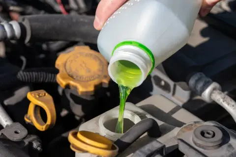 Main verte versée dans le réservoir, assurant le bon niveau liquide de refroidissement du moteur.