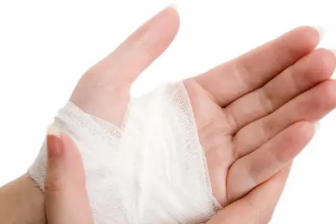 Dłoń z opatrunkiem na nadgarstku, pokazującym różne sposoby bandażowania.