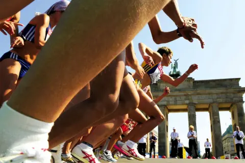 Biegaczki startują do maratonu pod Bramą Brandenburską. Słychać hasła dopingujące biegaczy, którzy walczą o zwycięstwo.