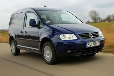 Ciemnoniebieski Volkswagen Caddy 3 w ruchu drogowym, z widocznym kierowcą.