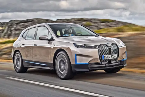 Elegancki suv BMW iX jedzie drogą wśród skalistych wzgórz.