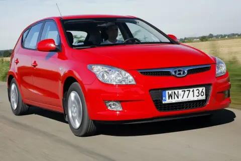 Czerwony Hyundai i30 1.6 CRDi jedzie po drodze wśród pól.