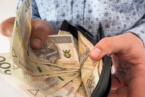 Ręce trzymają portfel z banknotami 200 zł. To nagroda jubileuszowa za 15 lat pracy, symbol docenienia za lata zaangażowania.
