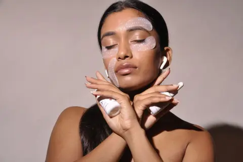 Donna con cerotti per il contorno occhi e creme, per combattere il viso stanco. Rimedi di bellezza per un aspetto radioso.