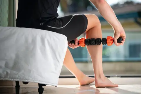 Un athlète utilise un rouleau de massage pour un massage de récupération sur sa jambe.