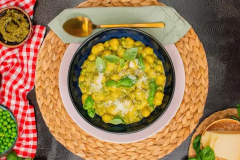 Gnocchi mit Erbsen und Basilikum-Pesto, garniert mit Parmesan. Ein köstliches Gericht, das Lust auf mehr macht.