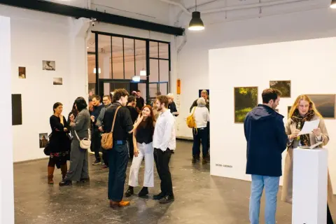 Besucher auf einer **Foto Messe Hamburg** diskutieren Kunstwerke in einer hellen Galerie.