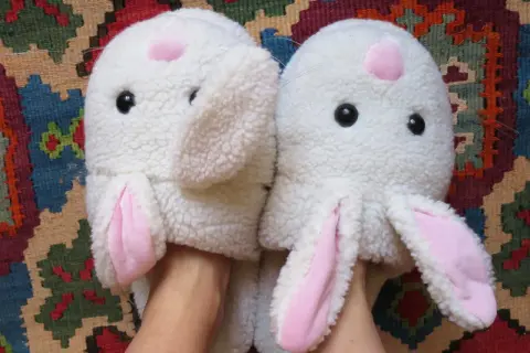 Pantofole a forma di coniglio bianco con orecchie rosa, pronte per essere lavate in lavatrice.